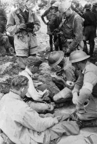Members of New Zealands 5th Field Ambulance attending to German Paratrooper casualties under olive trees on Crete. Photographed by an unknown photographer in 1941.