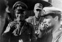 The German General, Erwin Rommel, lifting a glass in salute to the photographer, as he takes a drink with military colleagues on campaign in Libya, North Africa. Photographed by an unknown photographer about 1941.