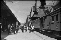 Group of soldiers boarding a troopship, with a train on the wharf alongside the ship.  Photograph taken by Albert Percy Godber