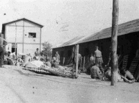 Camp 52 for POWs, Chaivari, Italy. Photograph taken by W A Weakley.  Note on back of file reads ''All beds and gear out for a sear. Note where bed slats have been taken off to provide fuel for brewing tea''
