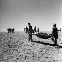 Soldiers carrying wounded on stretchers, Minqar Qaim, Egypt.  Photograph taken by H Paton in June 1942