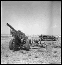 German field gun, and half-tracked tractor, knocked out by New Zealand Artillery during World War 2. Photograph taken near Gabes, Tunisia, by H Paton. Note on back of file print reads: 'A heavy German field gun (170mm?) and half tracked tractor, knocked out by N Z Artillery near Gabes.'