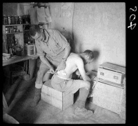 New Zealand medical officer attending to a patient's back at a regimental aid post, Western Desert, Egypt, during World War 2. Photograph taken circa 1941. This aid post was part of the network of underground offices and concealed positions dug by New Zealanders in the Western Desert.