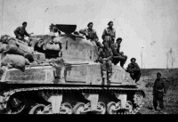 Soldiers of 18th Armoured Regiment, C Squadron, and tank no 7, ready to cross the Po River in Italy.  From left to right (excluding the man on the tank behind, at far left, and the man on the ground, on far right): Meave Davis, Allan Williamson, Bill Lynn, Spud Crispin, George Kimberly. Taken by an unidentified photographer during World War II.