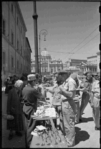 World War 2 New Zealand soldiers, S S Limmer, and R A Coon, looking at souvenirs in Rome while on leave. St Peter's is in the background. Photograph taken by George Kaye in 1944, circa 2 July.