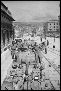 New Zealand tanks on a street in Trieste, Italy, towards the end of World War II. Shows Sherman tanks and New Zealand soldiers from 19 Armoured Regiment. Photograph taken circa 4 May 1945 by George Frederick Kaye.
