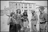 Italian (Partisini?/Partisni?) women, with rifles and captured German stick grenades, talking with New Zealand troops at Massa Lombarda, Italy, after the town fell to New Zealand troops. Shows soldiers A Burton of Wellington and Frank Stewart of Dunedin.  Photograph taken circa 13 April 1945 by George Frederick Kaye.  Note on back of file print reads: 