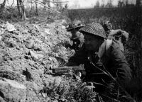 Lieutenant S W Turnbull (Gore) and N F Miles (Chch), of 26 New Zealand Battalion, in a slit trench waiting for the word to advance while the battle continues just over 100 yards away.  Photograph taken by George Kaye, in the Senio area, Italy, 10 April 1945.  Note on back of file print reads: 