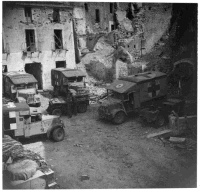 Ambulances of 5th New Zealand Advanced Dressing Station, 5th New Zealand Field Ambulance, parked in the shelter of buildings at San Elia, near Cassino, Italy.  Photograph taken by K G Killoh in 1944.  Defence Archive print caption reads: 