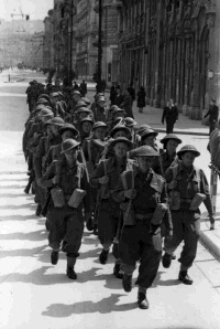 Shows the New Zealand infantry, in full battle kit, marching in Trieste, Italy, May 1945 with Lt. John Sefton leading and Les Jesson fourth from front in centre row.