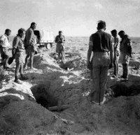 A burial service at El Alamein, Egypt, taken by Roman Catholic padre Forsman. Shows graves and soldiers (probably from the 5th Field Ambulance) standing by.  Photograph taken by K G Killoh on 24 October 1942.  Historical Note: Padre Forsman was attached to 5 NZ Main Dressing Station