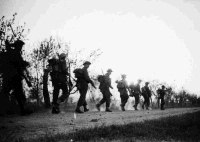 New Zealand infantrymen moving into the attack against ememy held positions on the Senio River sector, Italy. The sun is setting.  Note on back of file print reads: 