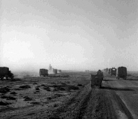 A scene at the instant a truck struck a land mine, showing the dust and smoke of the explosion forming a darker cloud in the clouds of sand raised by the convoy.  Photograph taken by H Paton at Mersa Matruh, 3 December 1942.  Inscribed - Verso - `Taken at the instant a truck struck a land mine, the dust and smoke of the explosion forms a darker cloud in the clouds of sand raised by the convoy outside Mersa Matruh during the opening of the 8 Army pursuit of the Axis forces in November'.