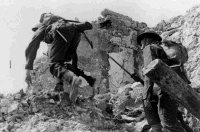 Two soldiers on the battlefront at Cassino, Italy, during manoeuvres. Probably taken during a mock attack staged behind the line.  Photographed by George Kaye, 5 April 1944.